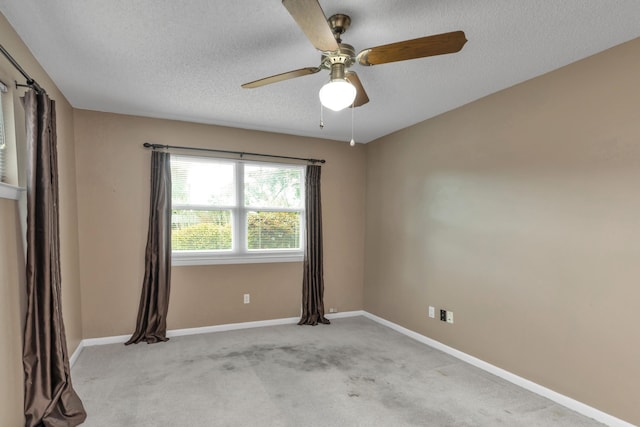 carpeted spare room featuring a textured ceiling, ceiling fan, and baseboards