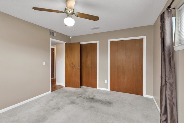 unfurnished bedroom with baseboards, visible vents, multiple closets, and carpet flooring