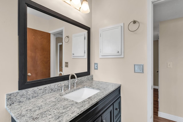 bathroom featuring baseboards, wood finished floors, and vanity