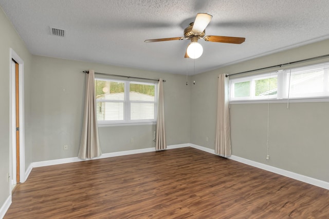 empty room featuring baseboards, wood finished floors, visible vents, and a healthy amount of sunlight