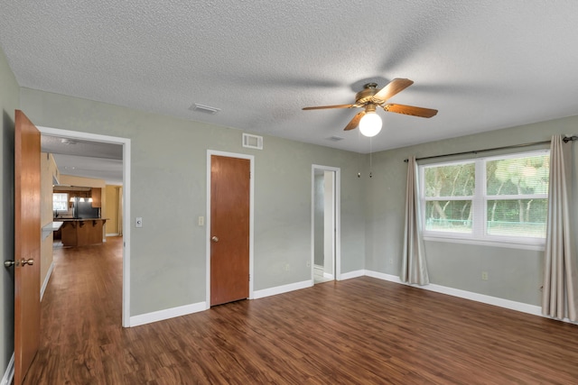 unfurnished bedroom with dark wood-type flooring, fridge, visible vents, and baseboards