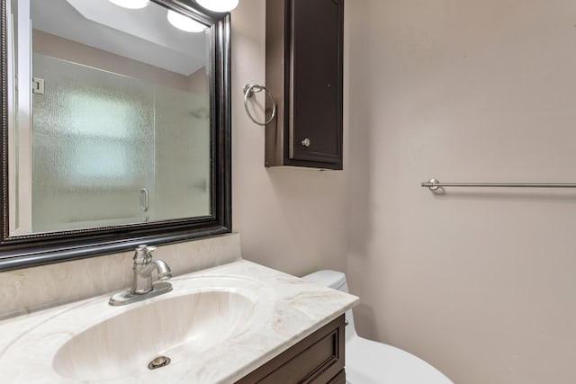 bathroom featuring toilet, a shower with door, and vanity