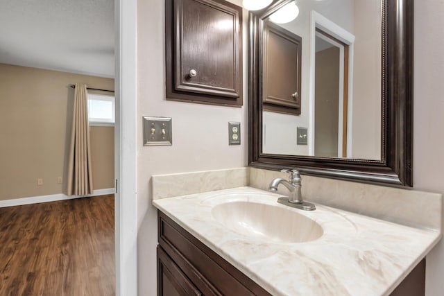 bathroom featuring wood finished floors, vanity, and baseboards