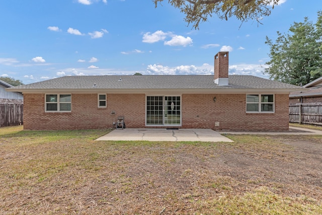 rear view of house featuring a patio area, a chimney, fence, and brick siding