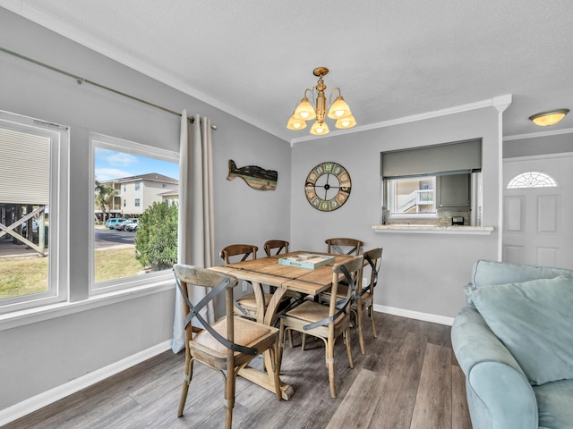 dining room with ornamental molding, a textured ceiling, wood finished floors, a chandelier, and baseboards