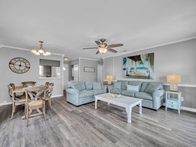 living room with ceiling fan with notable chandelier, ornamental molding, wood finished floors, and baseboards