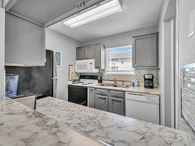 kitchen with gray cabinets, white appliances, a sink, and tasteful backsplash