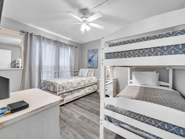 bedroom featuring a textured ceiling, wood finished floors, and a ceiling fan