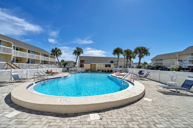 community pool with a patio area, fence, and a residential view