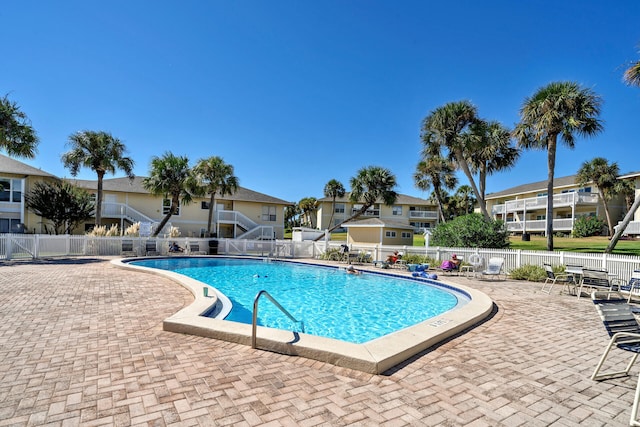 pool with a patio, fence, and a residential view