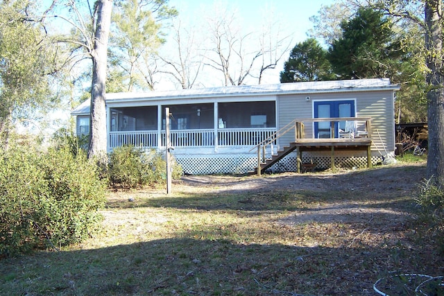 rear view of house with a lawn, stairway, a wooden deck, and a sunroom