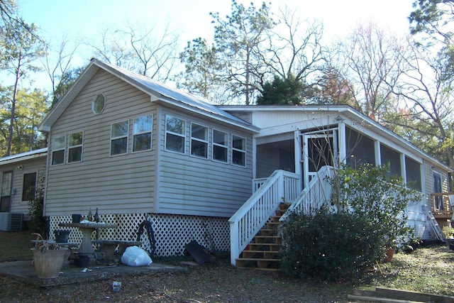 view of front facade with a sunroom, stairway, and central AC unit