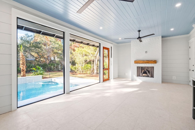 unfurnished living room with a ceiling fan, a wealth of natural light, wood ceiling, and a fireplace