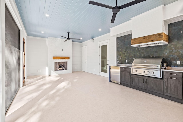 kitchen featuring a ceiling fan, stainless steel refrigerator, light countertops, dark brown cabinets, and a fireplace