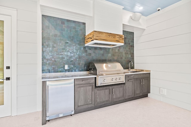 kitchen with dark brown cabinetry, refrigerator, a sink, light countertops, and custom range hood