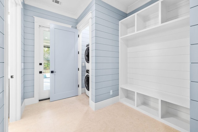 laundry room featuring stacked washer and clothes dryer, visible vents, wooden walls, and laundry area