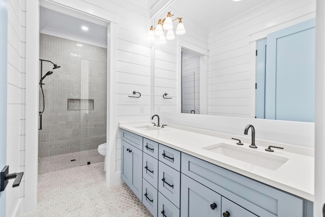 bathroom featuring double vanity, tiled shower, and a sink