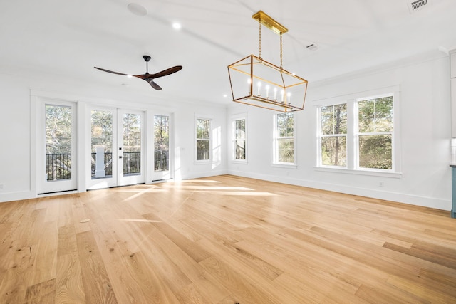 unfurnished living room with baseboards, crown molding, french doors, light wood-type flooring, and ceiling fan with notable chandelier