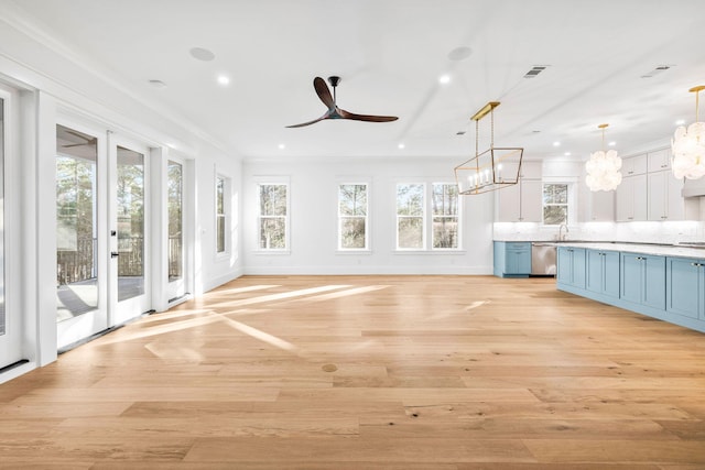 kitchen featuring white cabinets, light countertops, blue cabinetry, pendant lighting, and stainless steel dishwasher