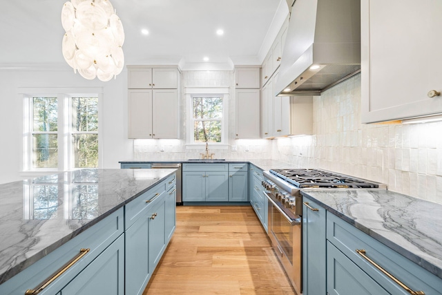 kitchen featuring white cabinets, dark stone counters, custom range hood, appliances with stainless steel finishes, and a sink