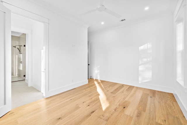 empty room featuring ceiling fan, visible vents, crown molding, and wood finished floors