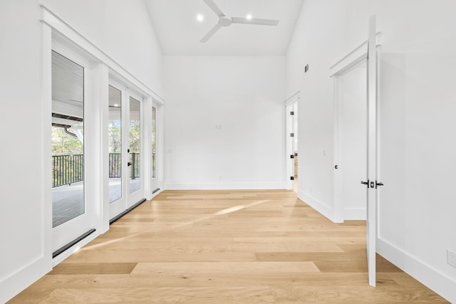 hall featuring light wood-style floors, baseboards, and french doors