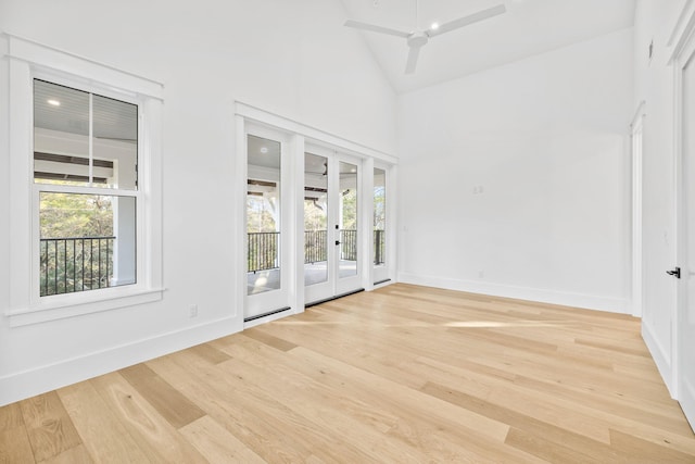 empty room with baseboards, high vaulted ceiling, french doors, and light wood-style floors