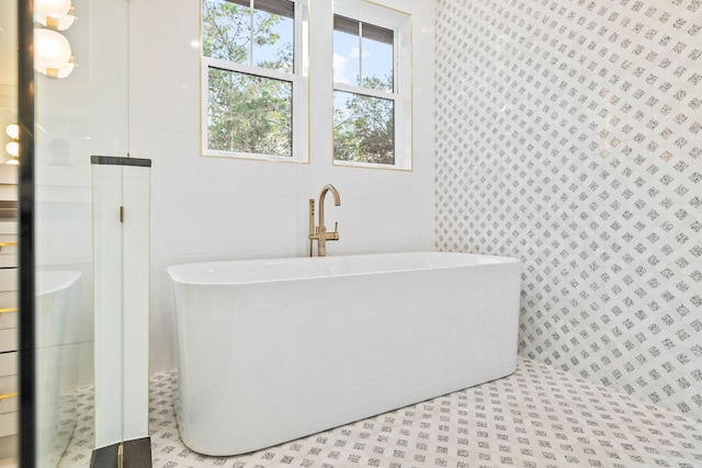 full bathroom featuring a freestanding tub, a tile shower, and tile walls