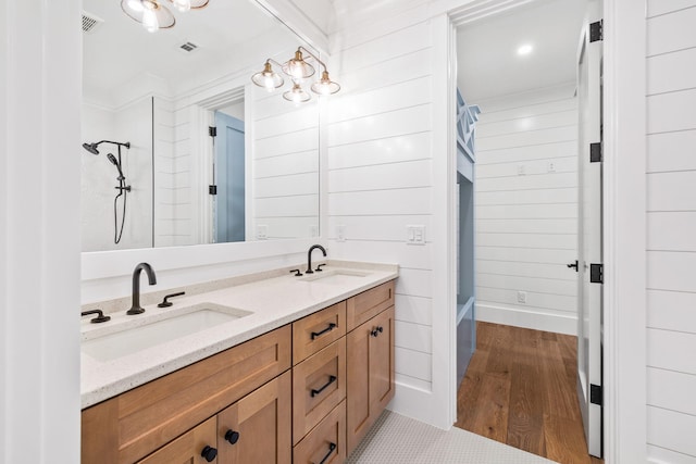 bathroom featuring double vanity, wood walls, visible vents, and a sink