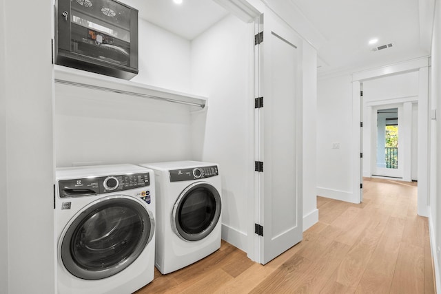 clothes washing area featuring light wood-type flooring, laundry area, visible vents, and independent washer and dryer