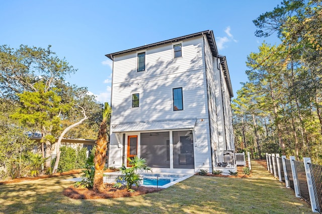 rear view of property featuring a sunroom, a fenced backyard, a fenced in pool, and a lawn