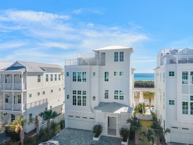 view of property with decorative driveway, a water view, and an attached garage