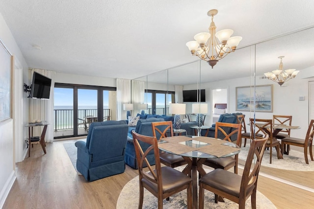 dining area with an inviting chandelier, a textured ceiling, baseboards, and light wood-style floors