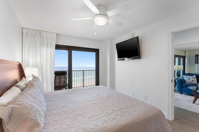 bedroom with a textured ceiling, wood finished floors, a ceiling fan, and access to exterior