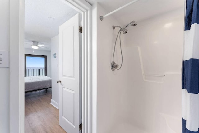 bathroom featuring wood finished floors, ensuite bath, a ceiling fan, and a shower stall