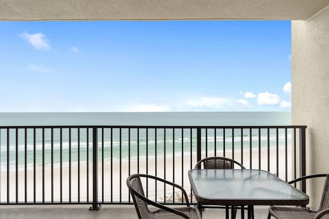 balcony with a water view and a view of the beach