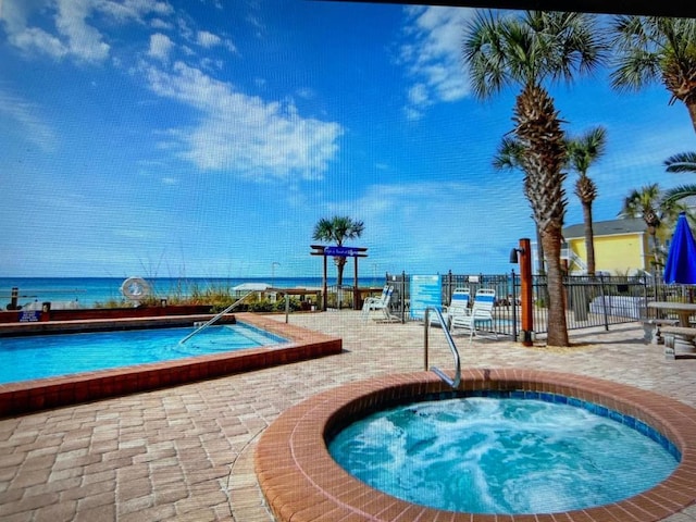 view of swimming pool featuring a water view, fence, a community hot tub, and a patio