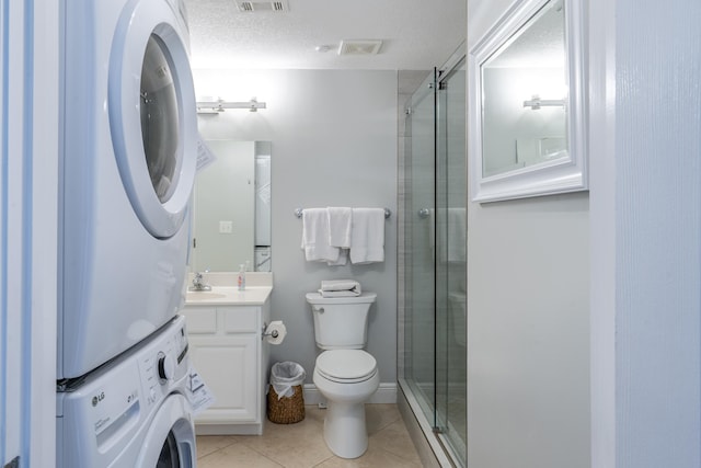 full bathroom with a stall shower, stacked washer and clothes dryer, vanity, and tile patterned floors