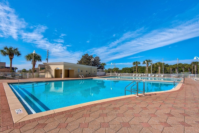 community pool with a patio area and fence