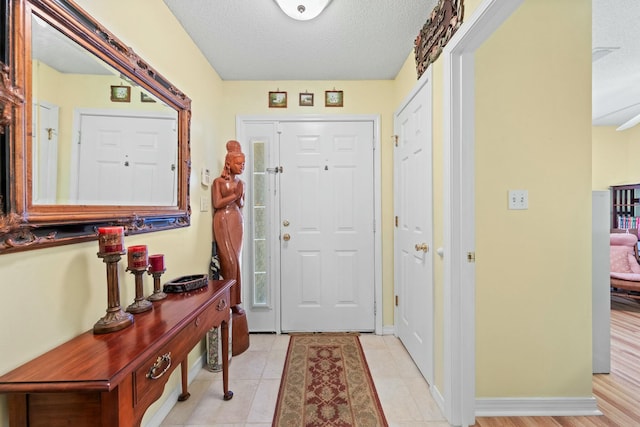 foyer with light tile patterned floors, baseboards, and a textured ceiling