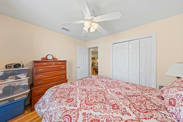 bedroom featuring a ceiling fan, a closet, visible vents, and light wood finished floors