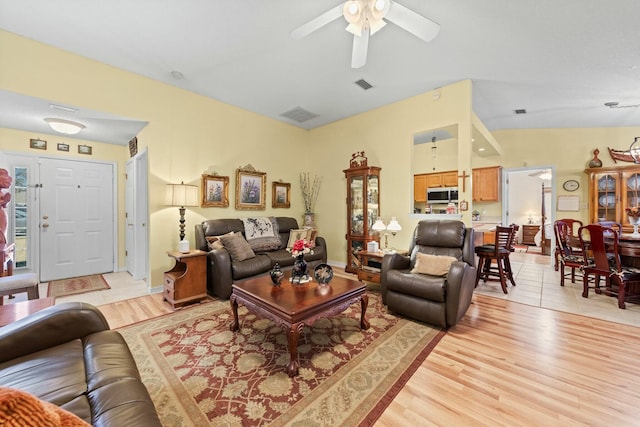 living area featuring light wood-type flooring, visible vents, and vaulted ceiling