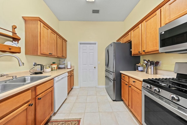 kitchen featuring light tile patterned floors, stainless steel appliances, light countertops, visible vents, and a sink