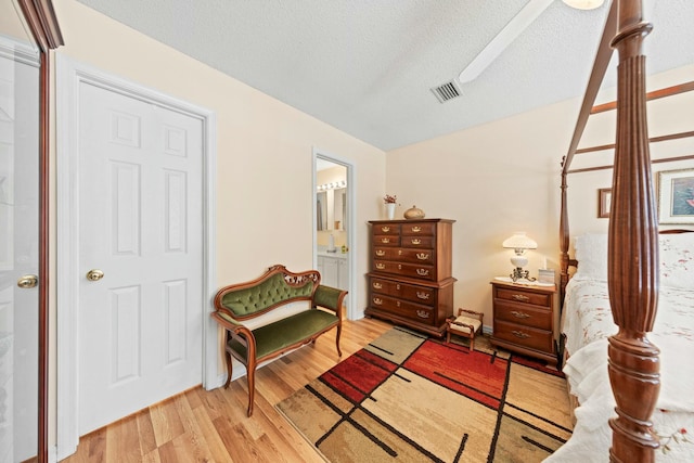 sitting room with visible vents, a textured ceiling, and light wood finished floors