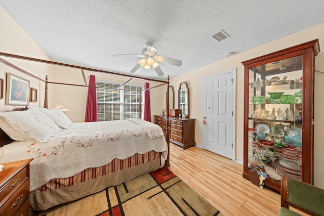 bedroom featuring a textured ceiling, ceiling fan, visible vents, and light wood-style floors