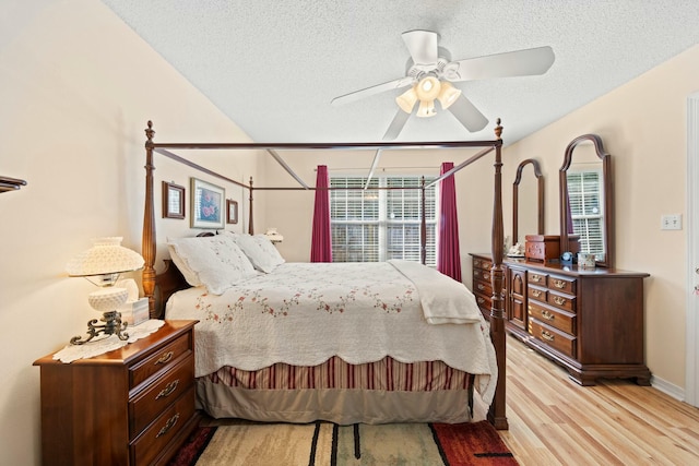 bedroom with light wood-style floors, a textured ceiling, and a ceiling fan