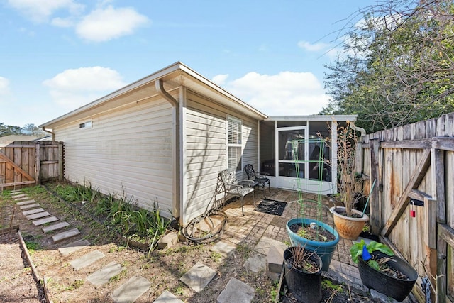 view of property exterior featuring a sunroom, a patio area, and a fenced backyard