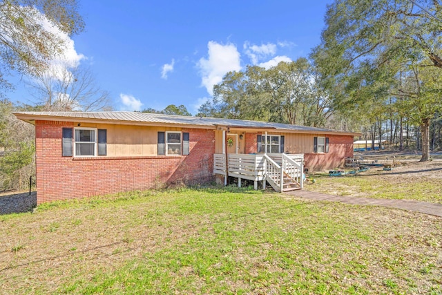 single story home with a deck, metal roof, brick siding, and a front yard