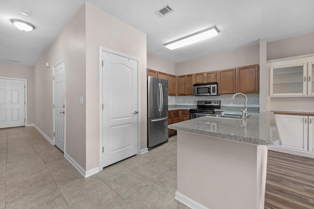 178 E Iron Horse Dr, Crestview, FL 32539 - kitchen with decorative backsplash, brown cabinetry, appliances with stainless steel finishes, a peninsula, and a sink