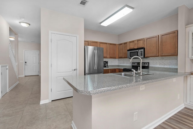 178 E Iron Horse Dr, Crestview, FL 32539 - kitchen featuring visible vents, appliances with stainless steel finishes, brown cabinets, a peninsula, and light countertops
